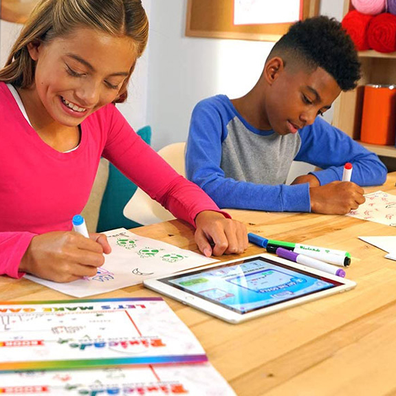 Two children are drawing on a book